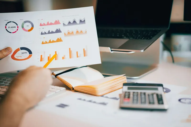 Rapport d'analyse imprimé avec graphiques, tenu au-dessus d'un ordinateur portable